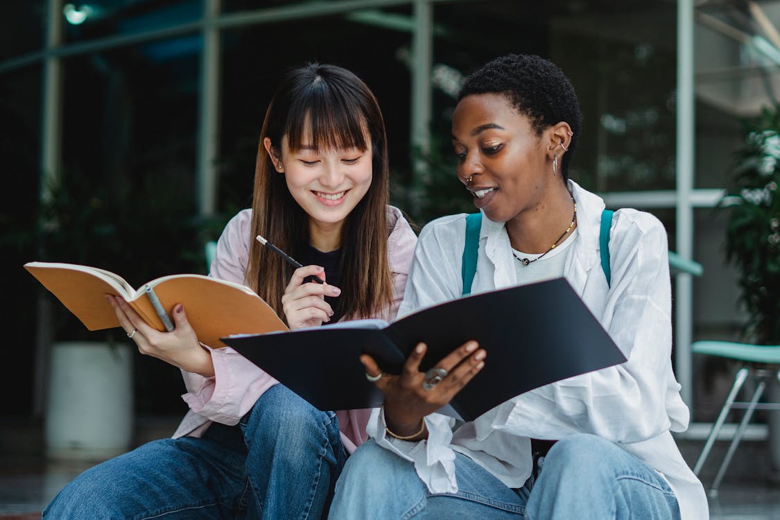Multiracial female students studying together outside