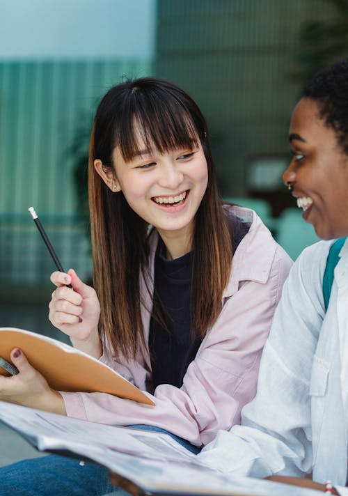 Multiethnic female friends talking and studying in street