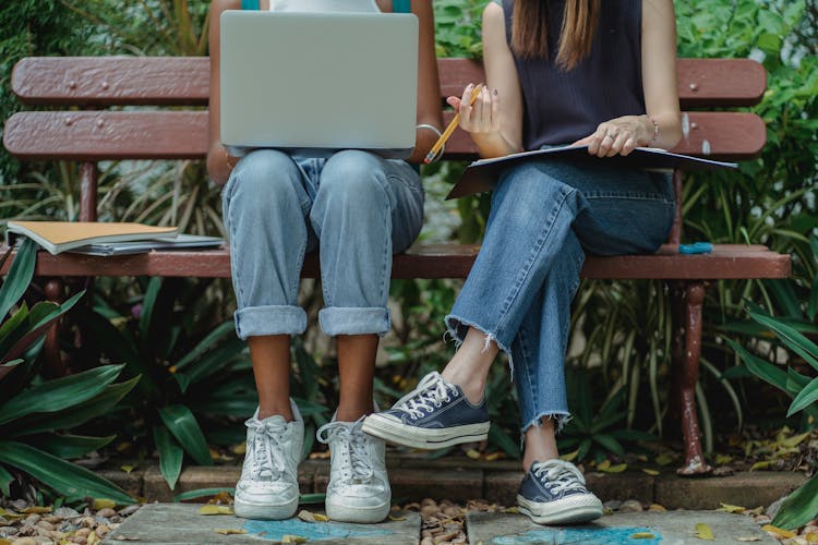 Diverse Students Using Laptop For Teamwork On Bench