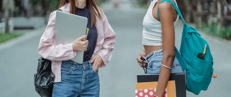 Diverse Girlfriends In Casual Wear Standing With Papers And Laptop