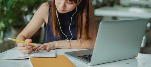 Macbook Proを使用して青いタンクトップの女性