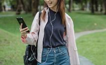 一位面带微笑的女子在公园里戴着耳机进行视频通话，享受着闲暇时光