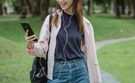 一位面带微笑的女子在公园里戴着耳机进行视频通话，享受着闲暇时光