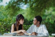 在郁郁葱葱的夏季花园里，几名穿着休闲装、来自不同种族的女学生围坐在桌旁，一边翻看教科书和文案，一边讨论着家庭作业