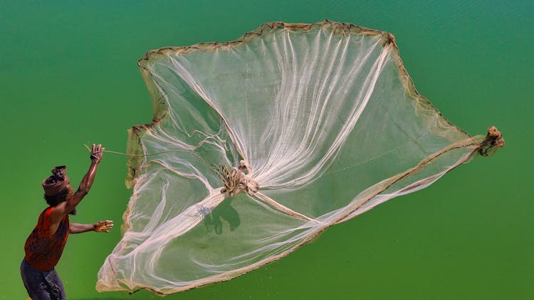 Man In Traditional Clothes Waving Fisherman Net