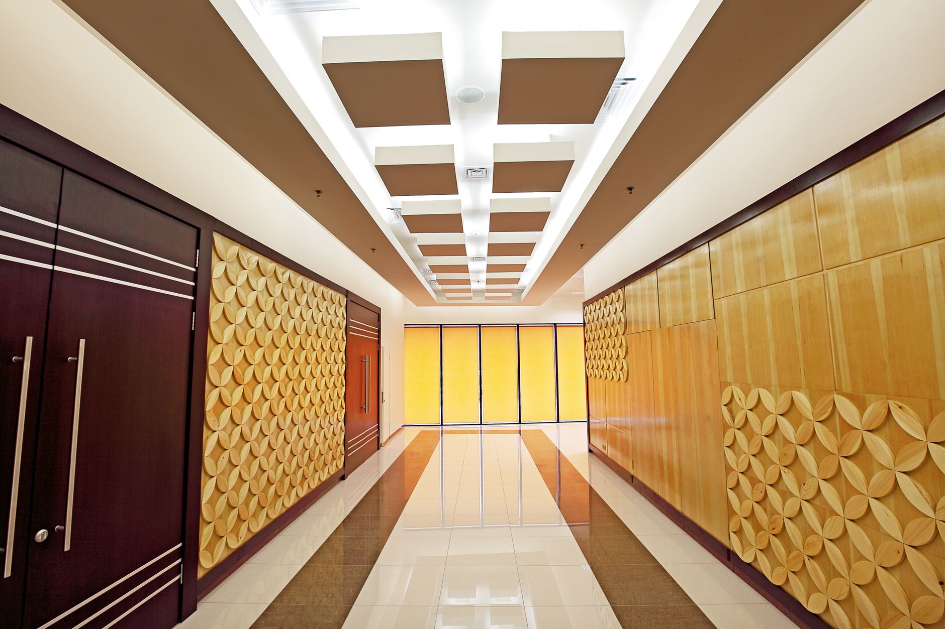 Elegant corridor in a luxury hotel featuring modern geometric wall decor and bright lighting.