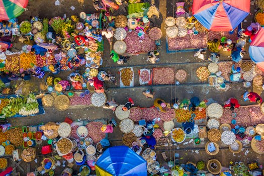 A bustling aerial view of a colorful local market with vendors and shoppers captured from above.
