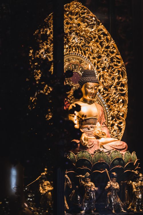 Free A beautifully ornamented golden Buddha statue in a dimly lit setting, showcasing spiritual artistry. Stock Photo