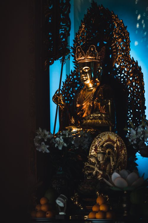 Free Beautiful bronze Buddha statue with intricate details illuminated against a blue backdrop. Stock Photo