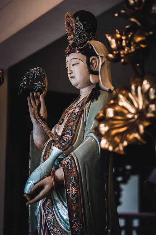 Free Intricate Asian statue depicting a serene spiritual figure, captured indoors with artistic lighting. Stock Photo