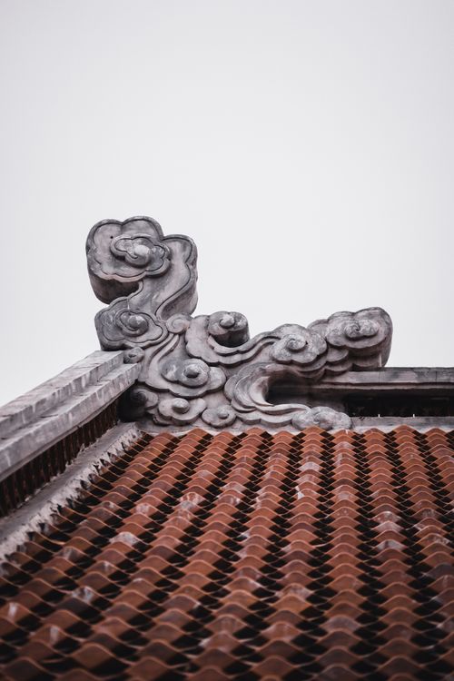 Free Close-up of an ornate roof with intricate stone carvings and terracotta tiles, creating a striking architectural detail. Stock Photo