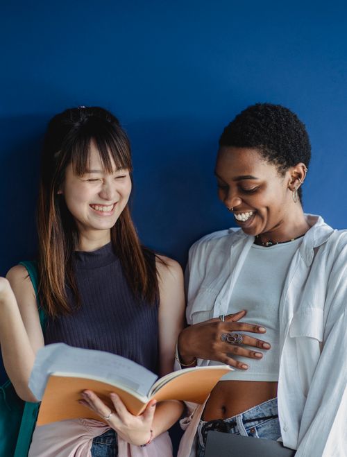 Free Two young women enjoying each other's company while reading together. Stock Photo