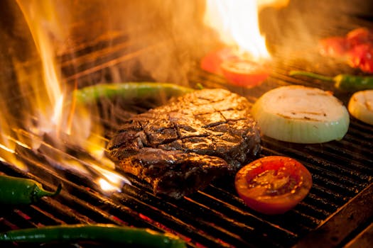 Flame-grilled steak with onions and tomatoes on a barbecue grill, ready to savor.