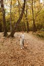 Woman in White Dress Walking on Brown Dirt Road With Brown Dog