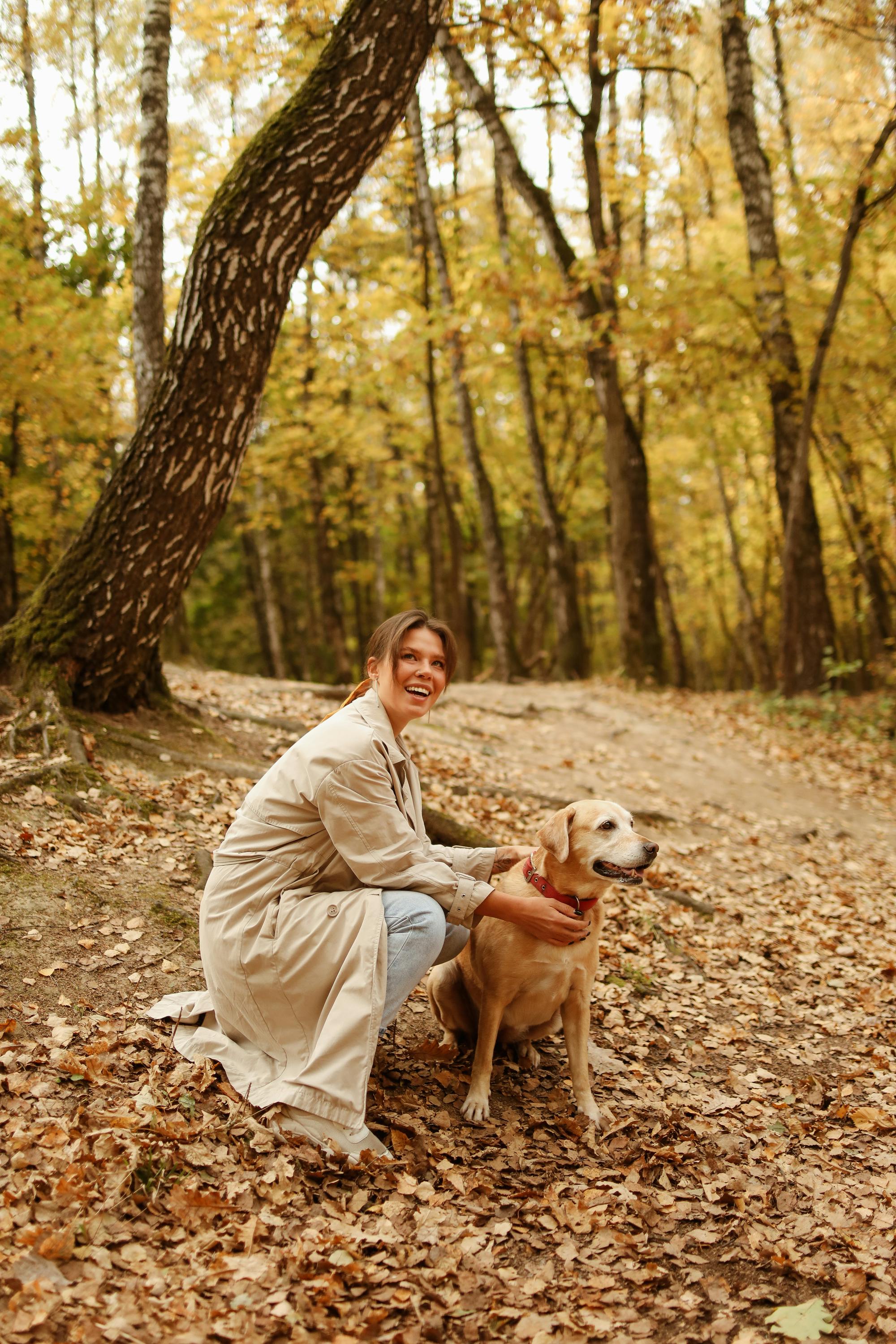 woman in brown coat touching her brown short coated dog