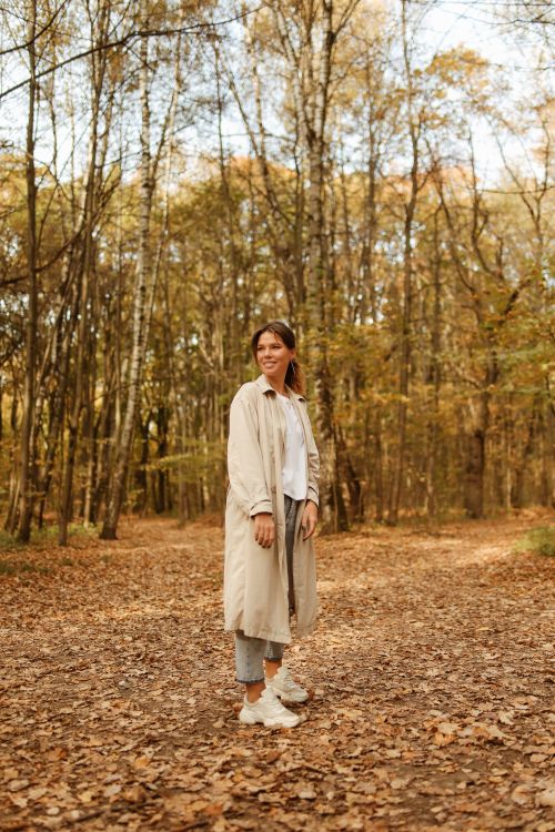 Free Smiling woman walking in an autumnal forest, surrounded by colorful trees and fallen leaves. Stock Photo