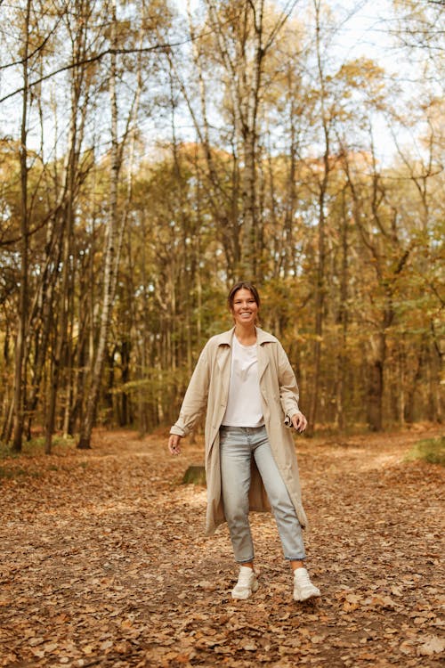 Happy Woman Standing on Ground Full of Dried Leaves 