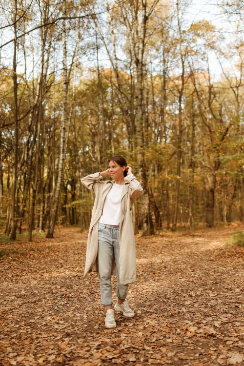 Free A woman enjoys a walk in the autumn forest, surrounded by falling leaves. Stock Photo