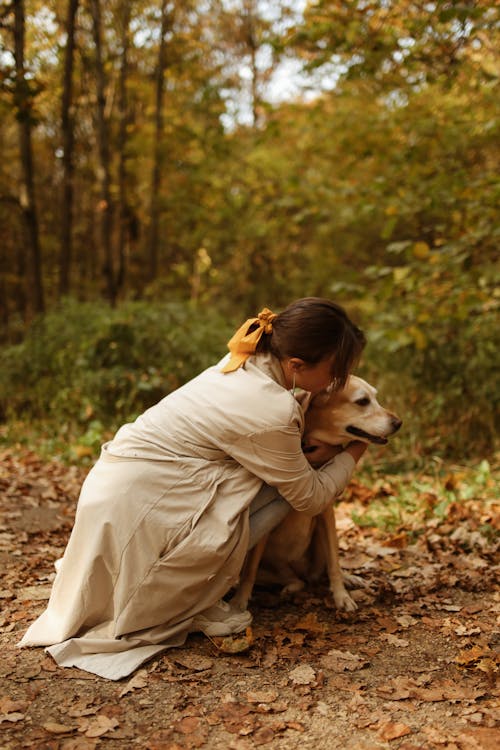 Woman Wearing Beige Coat Hugging the Labrador Retriever Dog
