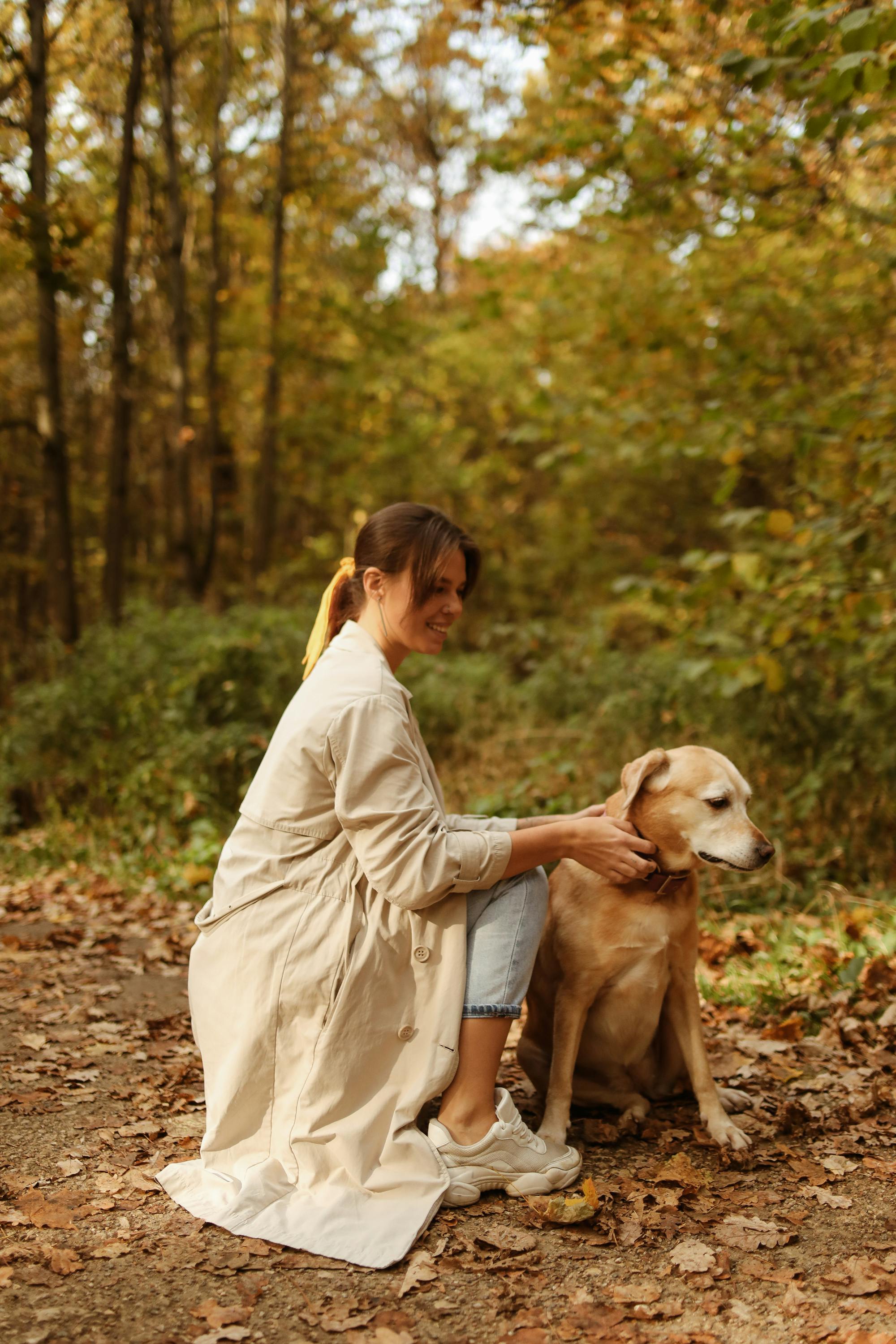 woman in beige trench coat touching her pet