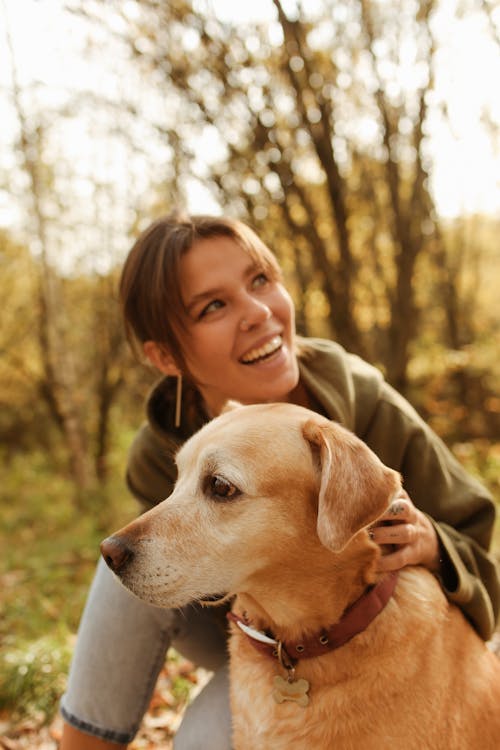 Free Woman in Green Jacket Holding Her Dog While Looking Up  Stock Photo