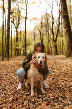 一位女士在宁静的秋日森林里拥抱着她的拉布拉多犬