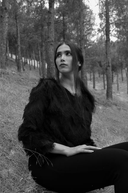 Black and white of dreamy thin pensive female looking away in pine forest