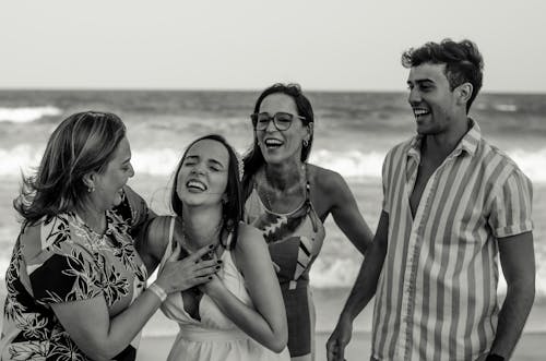 Black and white happy family standing together and laughing happily while reacting on news during vacation on beach