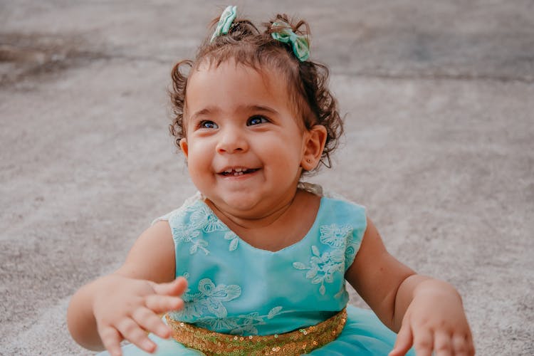 Cheerful Ethnic Baby In Trendy Wear Resting On Pavement