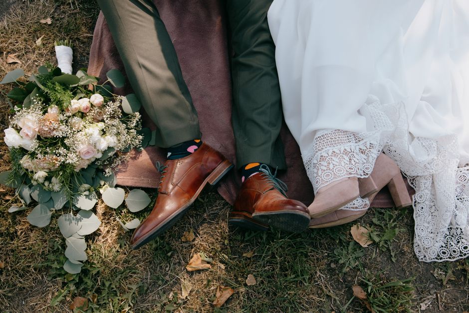 A couple's legs with a bridal bouquet, symbolizing newlyweds' romance outdoors.