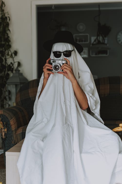 Person with old fashioned camera wrapped in white cloth