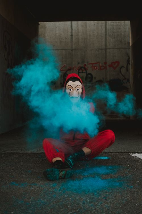 Free Full body of person hiding face under spooky mask while making clouds of color powder Stock Photo