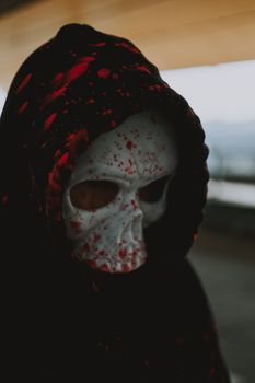 一个戴着可怕头骨面具、黑色兜帽溅满鲜血的身影，出现在神秘场景中