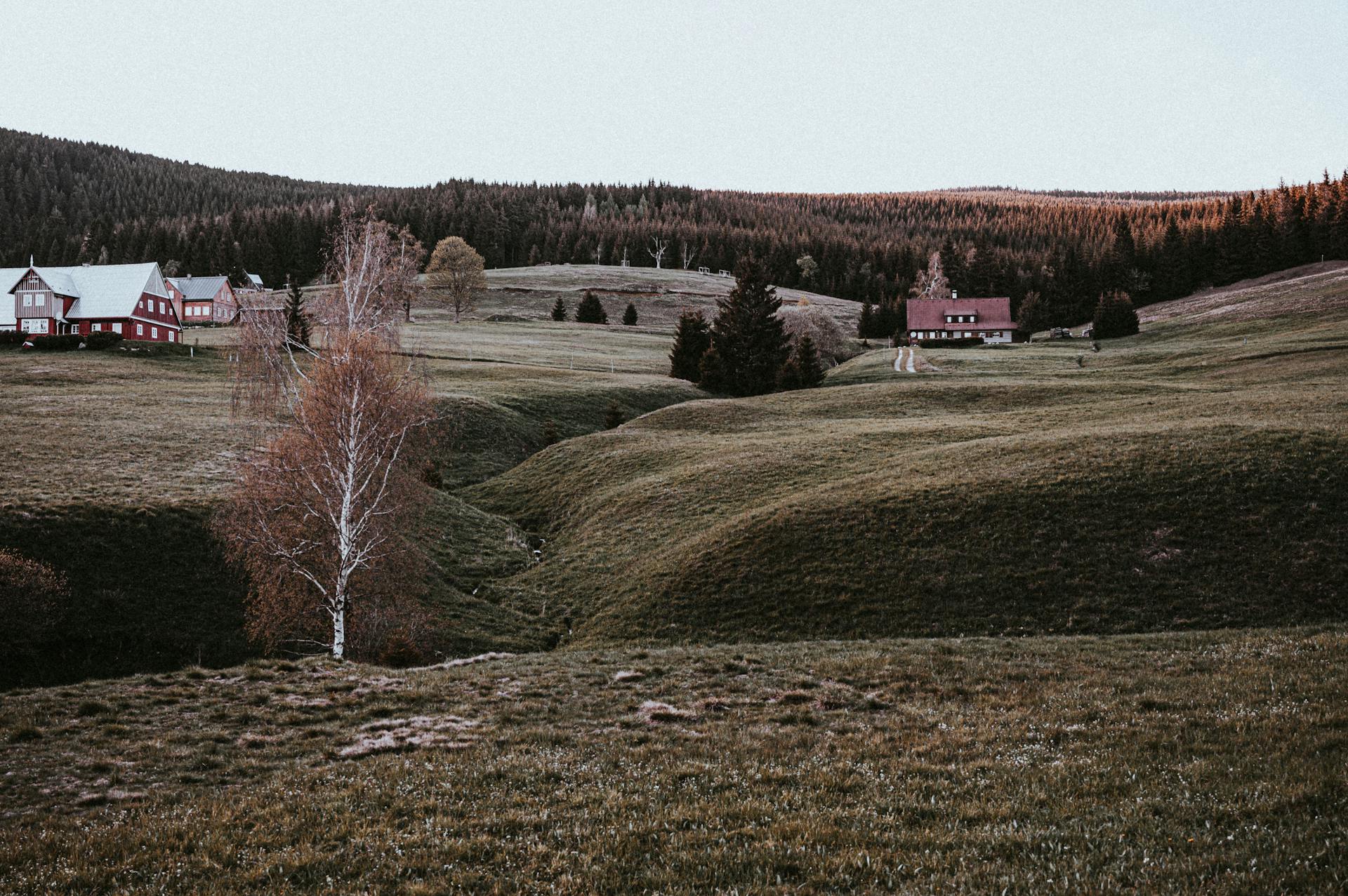 A serene rural landscape in Malá Úpa, Czechia, featuring green hills and quaint houses at dusk.