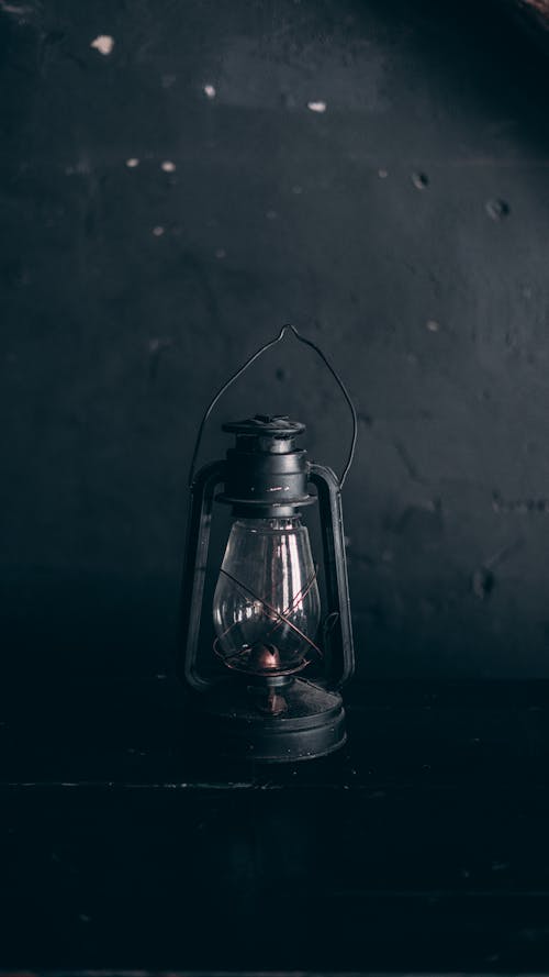 Free Black and white of vintage metal lantern lamp placed on dark wooden table at gray wall Stock Photo