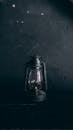 Black and white of vintage metal lantern lamp placed on dark wooden table at gray wall