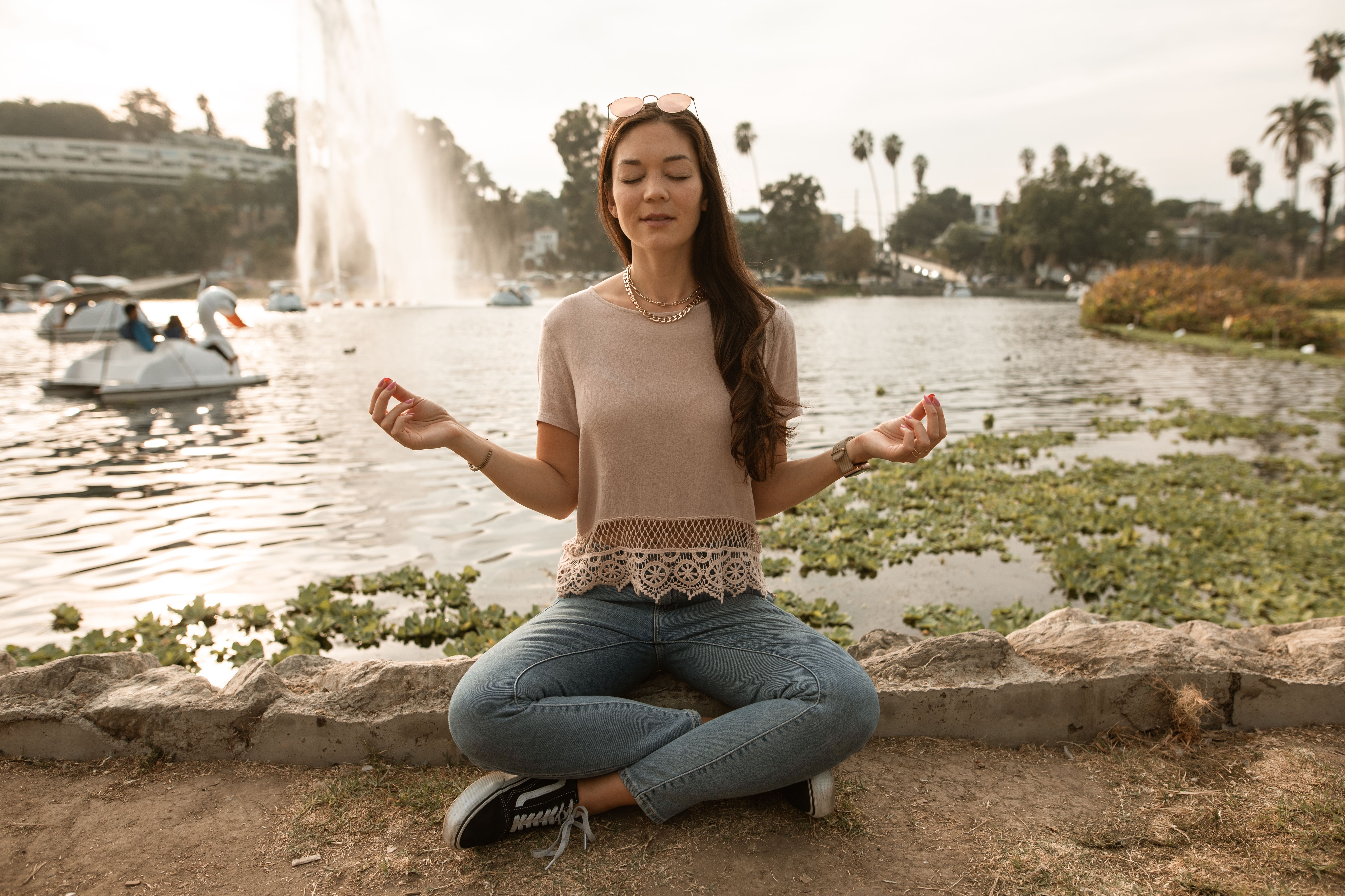 一名女子在公园宁静的湖边盘腿坐着冥想
