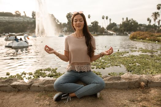 一名女子在公园宁静的湖边盘腿坐着冥想