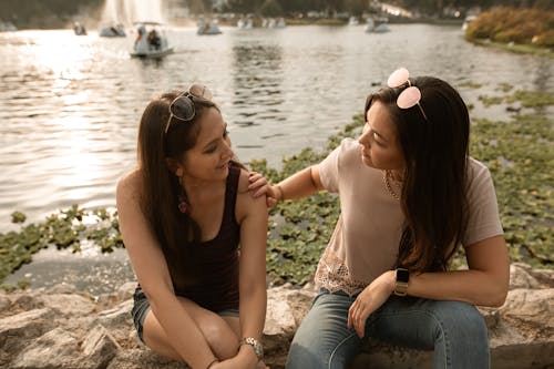 Free Women Sitting and Talking by a Lake Stock Photo