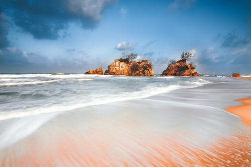 Free Waves washing shore against crags in sea Stock Photo