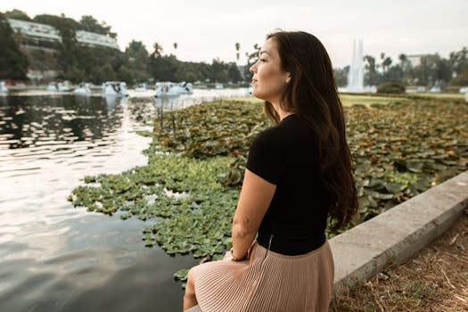 一名女子坐在湖边，周围郁郁葱葱的睡莲环绕，享受着平静的时刻