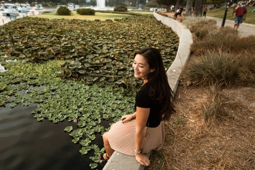 一位平静的女人坐在绿树环绕的湖边，沉浸在宁静与自我护理之中