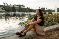 一个女人静静地坐在公园的湖边，享受着风景和宁静