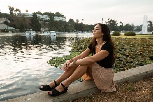 一个女人静静地坐在公园的湖边，享受着风景和宁静