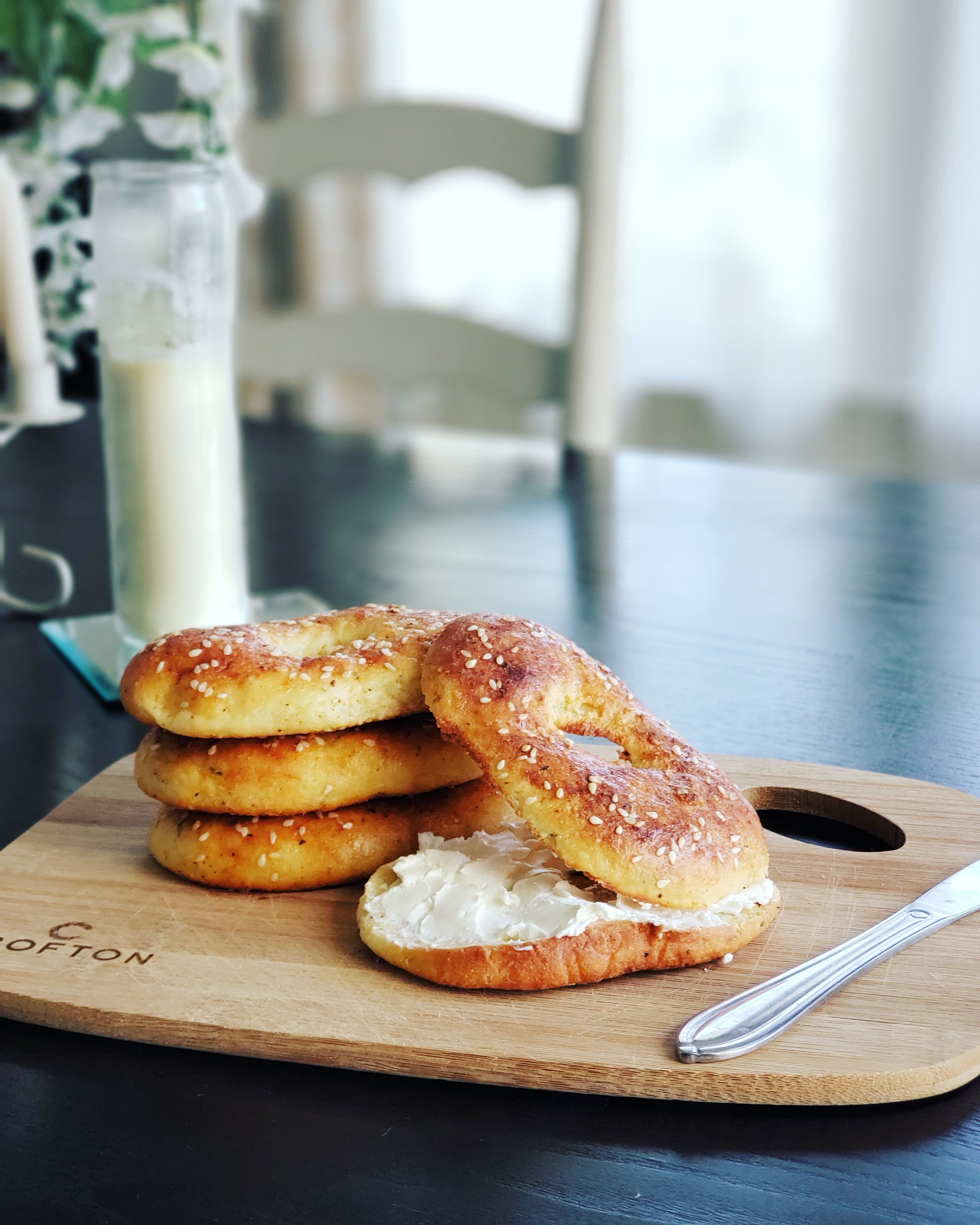 Fresh sesame bagels with cream cheese on a wooden board