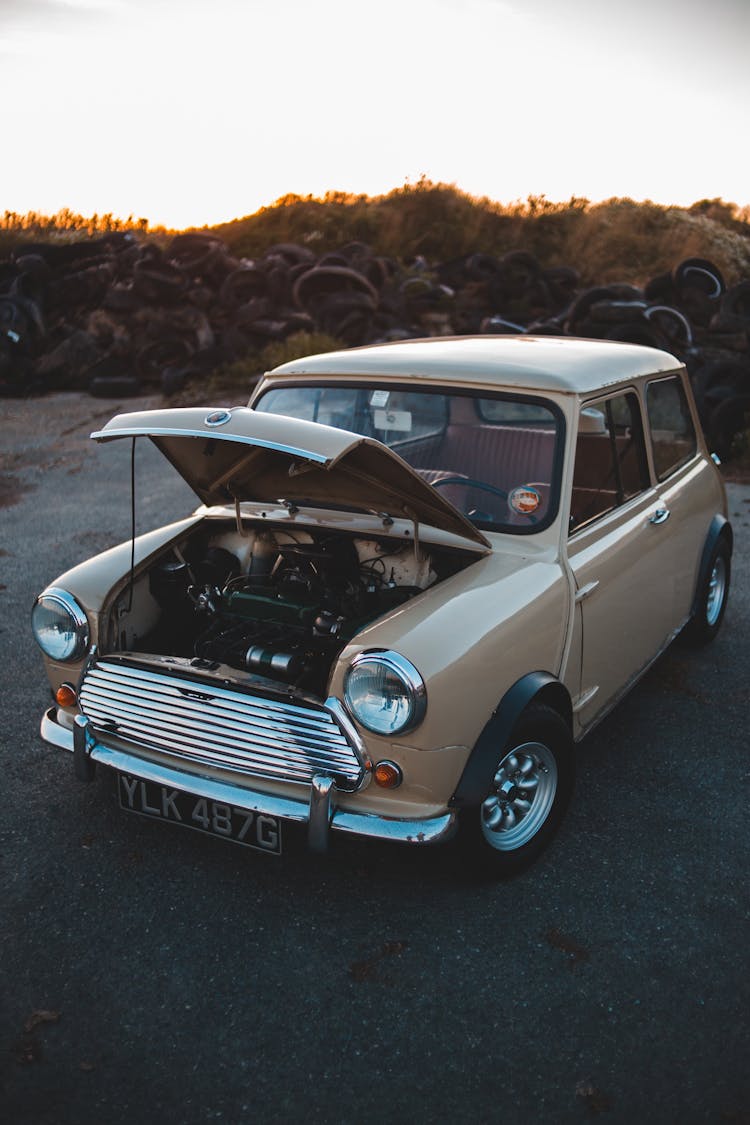 Vintage Car With Open Hood Against Old Car Tires