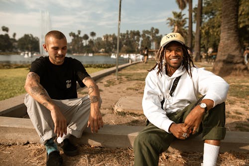 A Man in a Black Shirt Sitting Beside a Man with Dreadlocks