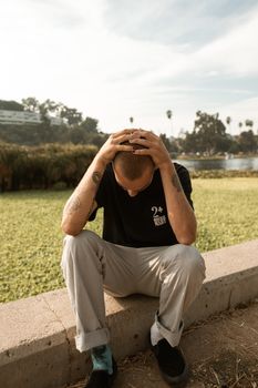 一名男子坐在户外，双手抱头，显得心事重重