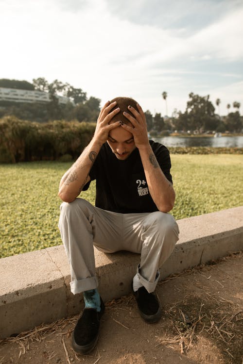 Man Holding his Head Sitting Outside