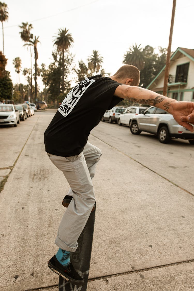 A Man In Black Shirt Riding A Skateboard